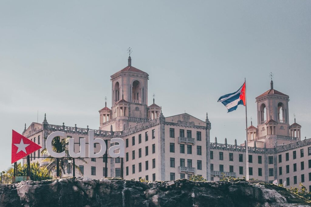 View of the historic Hotel Nacional in Havana, Cuba with a waving Cuban flag and clear sky.